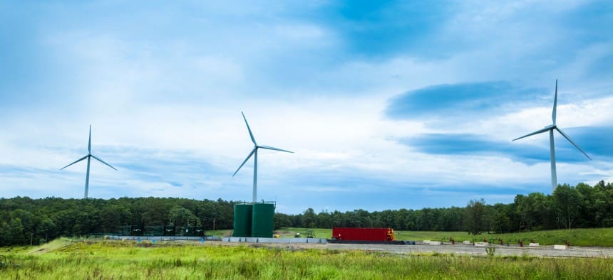 A wind turbine and a red truck in the middle of nowhere.